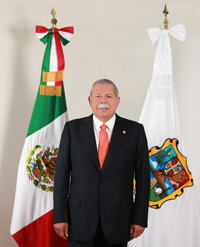 photo of Egidio Torre-Cantu standing in front of two flags