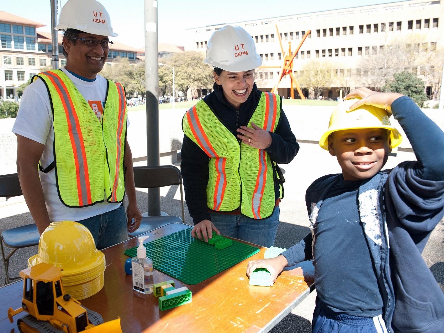 two students and elementary kid building with legos